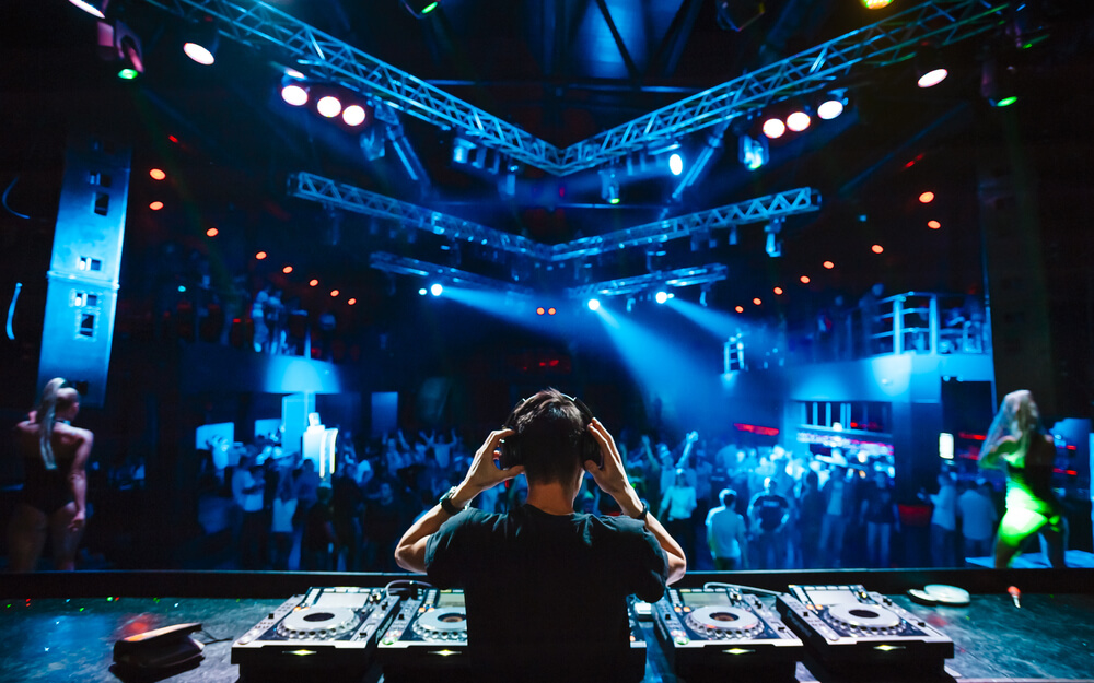 DJ avec un casque à la soirée club sous la lumière bleue et foule de gens en arrière-plan