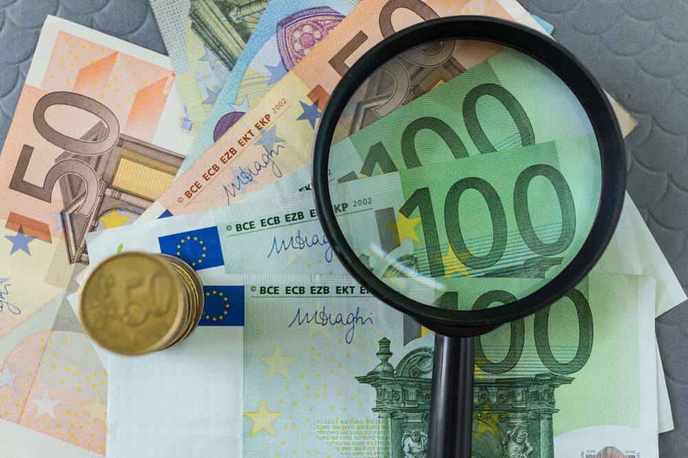Loupe sur pile de billets et de pièces en euros comme concept de taxe financière des entreprises