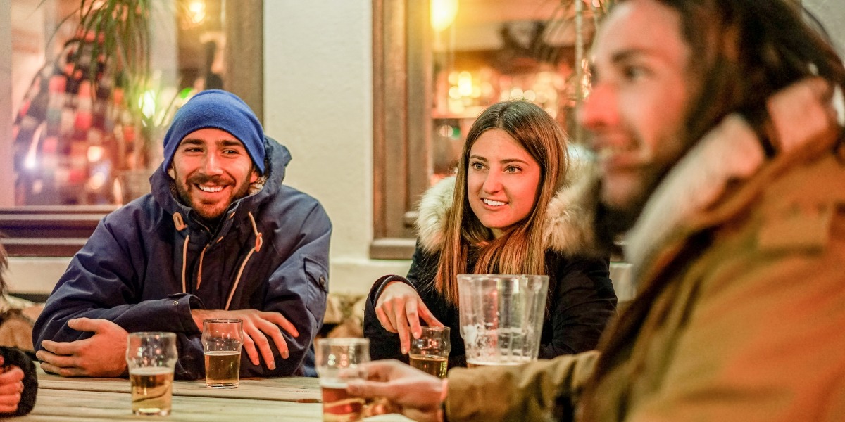 Jeunes grillage bières à chalet pub restaurant dans montagnes soir